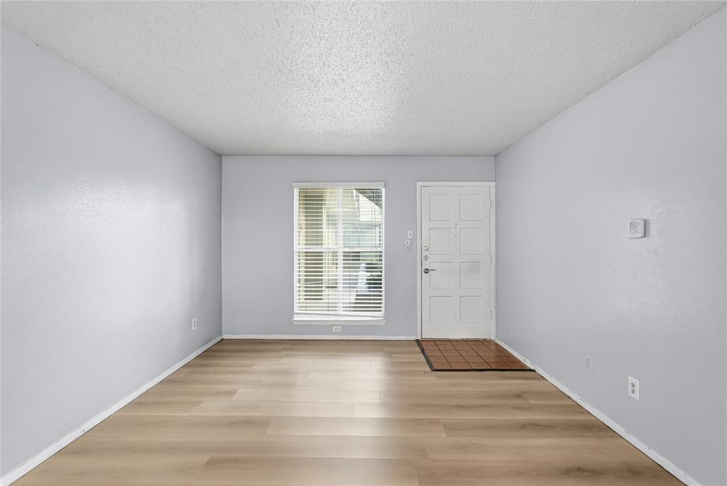 4211 Holland Avenue, Unit 105 Dallas, TX 75219 - Photo 6 of 26 a view of an empty room with wooden floor and a window
