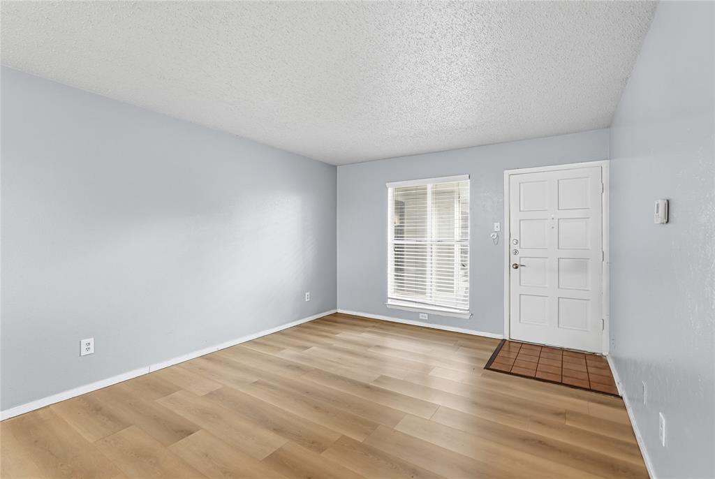 4211 Holland Avenue, Unit 105 Dallas, TX 75219 - Photo 7 of 26 a view of an empty room with wooden floor and a window
