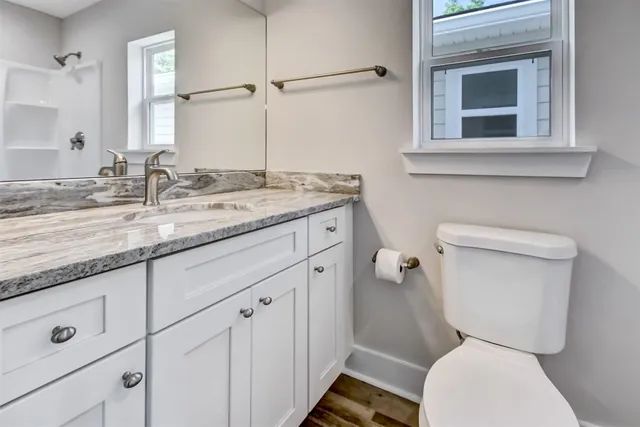 a bathroom with a granite countertop toilet sink and mirror