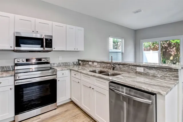 a kitchen with stainless steel appliances granite countertop a sink stove a microwave and cabinets
