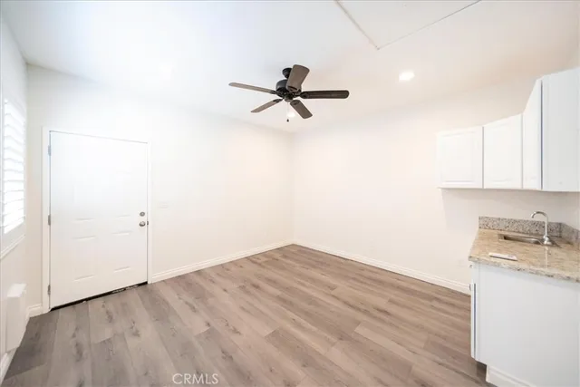a room with a chandelier fan and wooden floor
