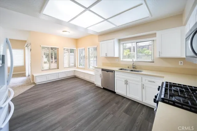 a large white kitchen with wooden floors and white stainless steel appliances