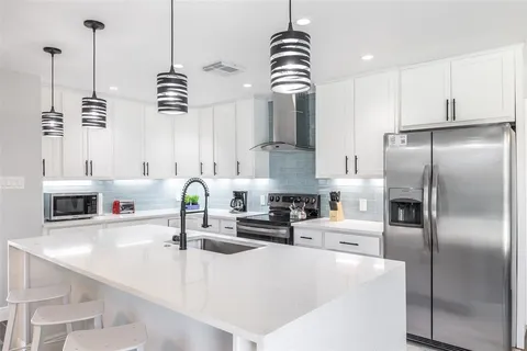 a kitchen with stainless steel appliances kitchen island granite countertop a sink a refrigerator and a counter top space