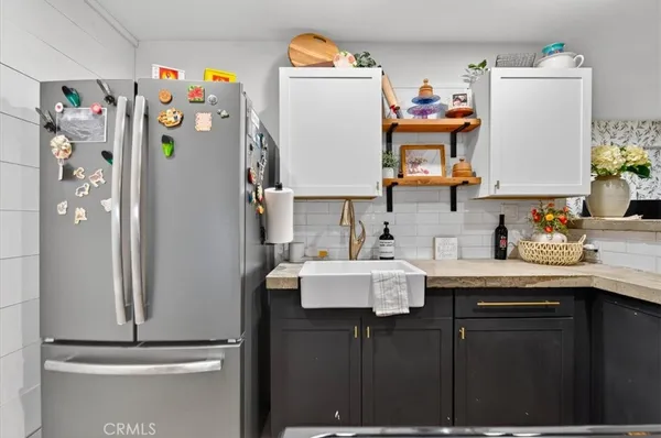 an empty room with wooden floor and way to kitchen