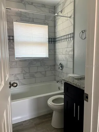 a bathroom with a granite countertop bathtub sink and toilet