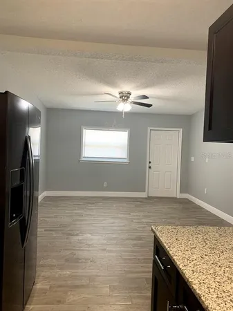 a view of kitchen island a sink wooden floor and a refrigerator