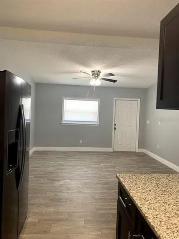 a view of kitchen island a sink wooden floor and a refrigerator