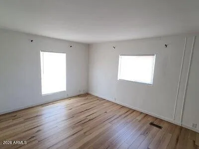 a view of an empty room with wooden floor and a window