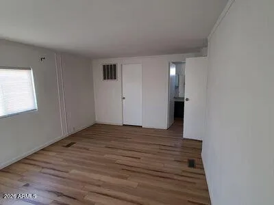 a view of an empty room with wooden floor and a window