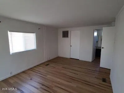a view of an empty room with wooden floor and a window