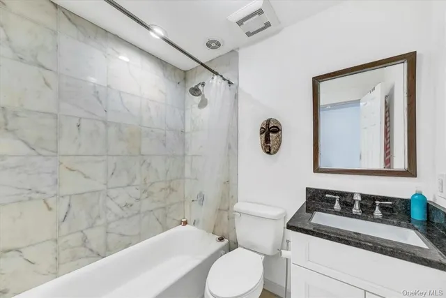 a bathroom with a granite countertop sink toilet a mirror and bathtub