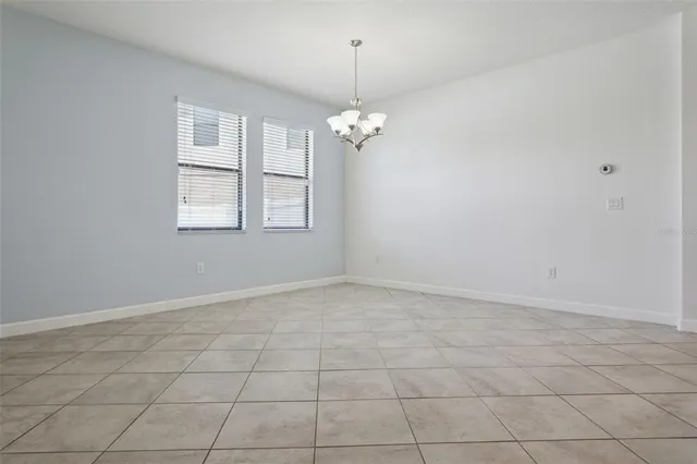an empty room with chandelier fan and windows