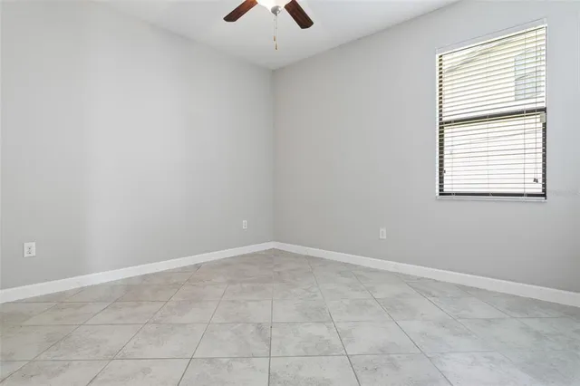 an empty room with chandelier fan and windows