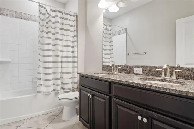 a bathroom with a granite countertop sink a toilet and shower