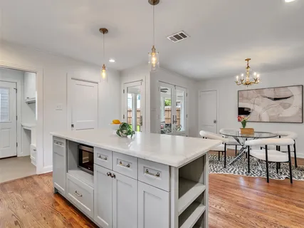 a kitchen with stainless steel appliances a white table chairs and a refrigerator