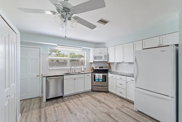 a kitchen with white cabinets and white appliances