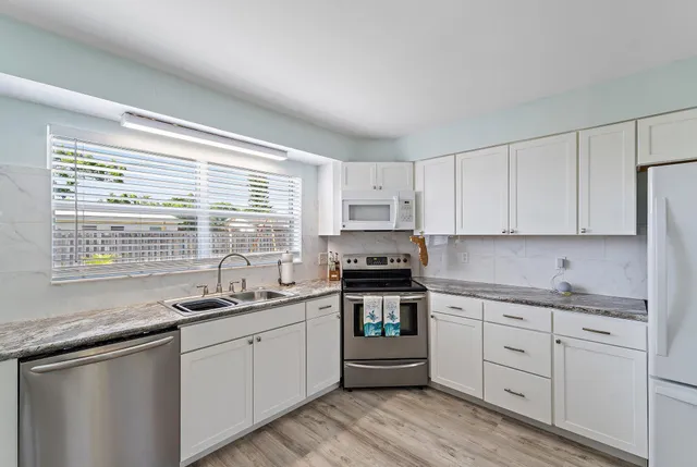 a kitchen with a sink stove cabinets and window