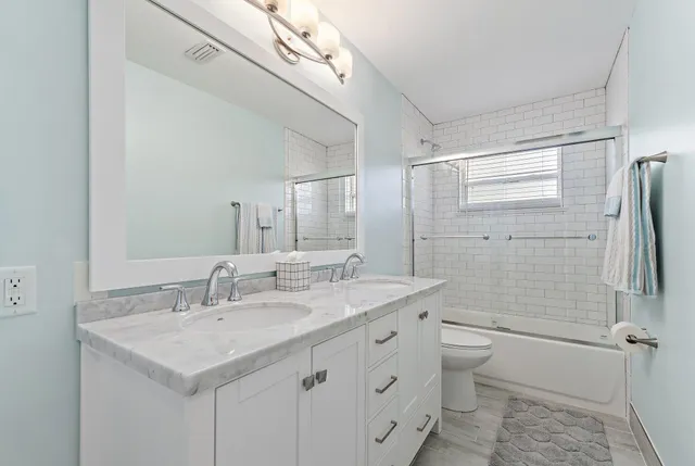 a bathroom with a sink toilet double vanity and shower
