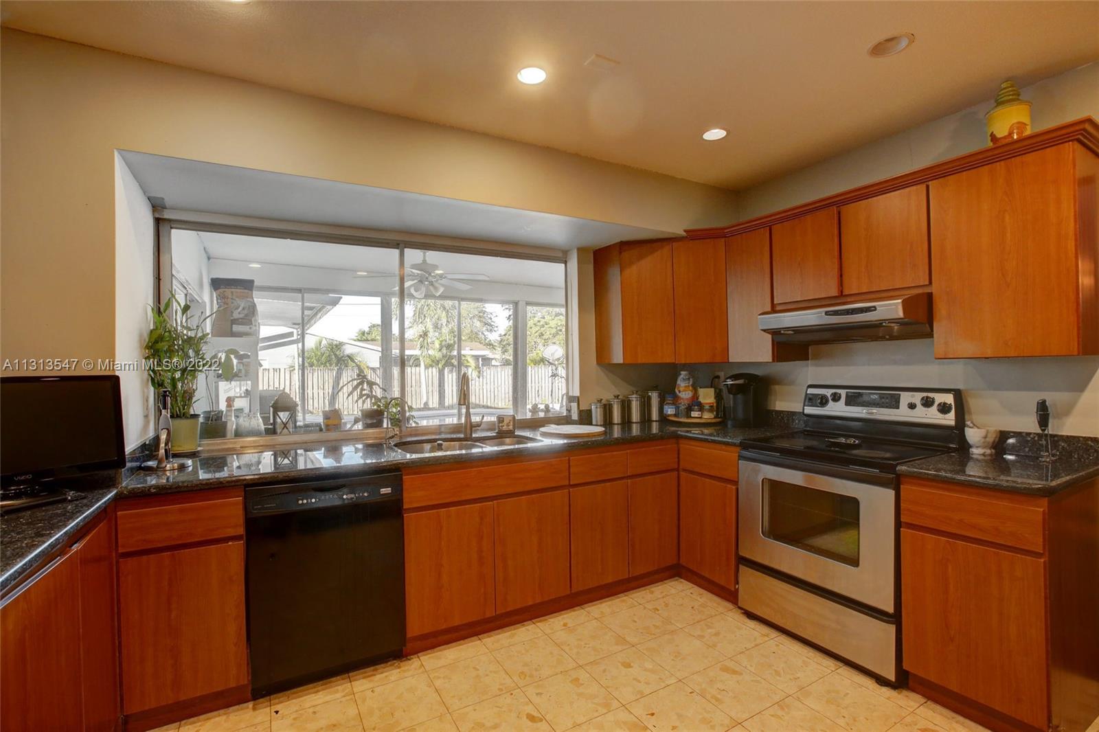 6681 Peters Road Plantation, FL 33317 - Photo 8 of 27 a kitchen with stainless steel appliances granite countertop wooden cabinets a sink a stove a granite counter top and a view of living room