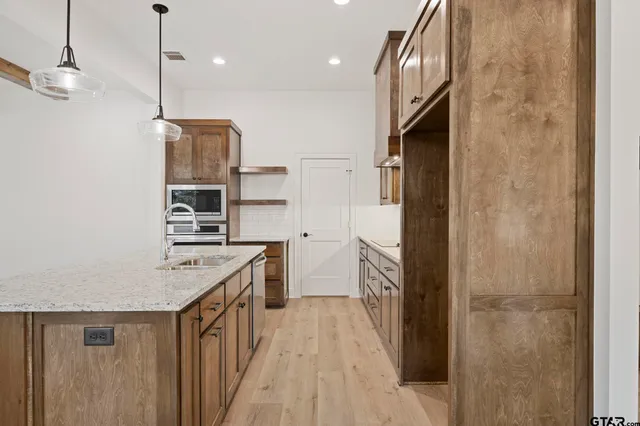 a kitchen with stainless steel appliances granite countertop a refrigerator a oven and a sink