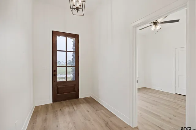 an empty room with wooden floor closet and windows