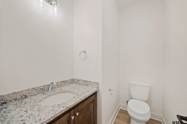 a bathroom with a granite countertop toilet and a sink