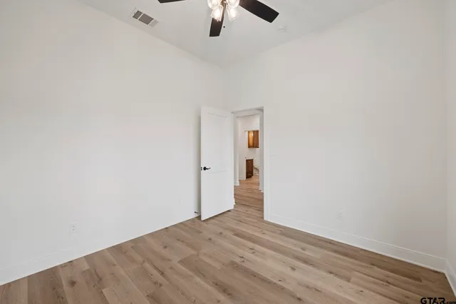 an empty room with a ceiling fan and wooden floor