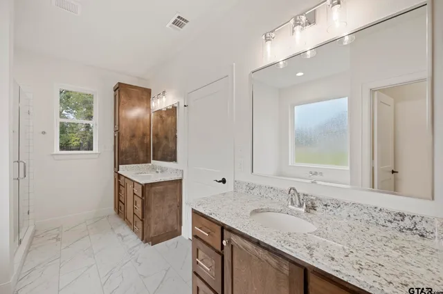 a bathroom with a granite countertop double vanity sink and mirror