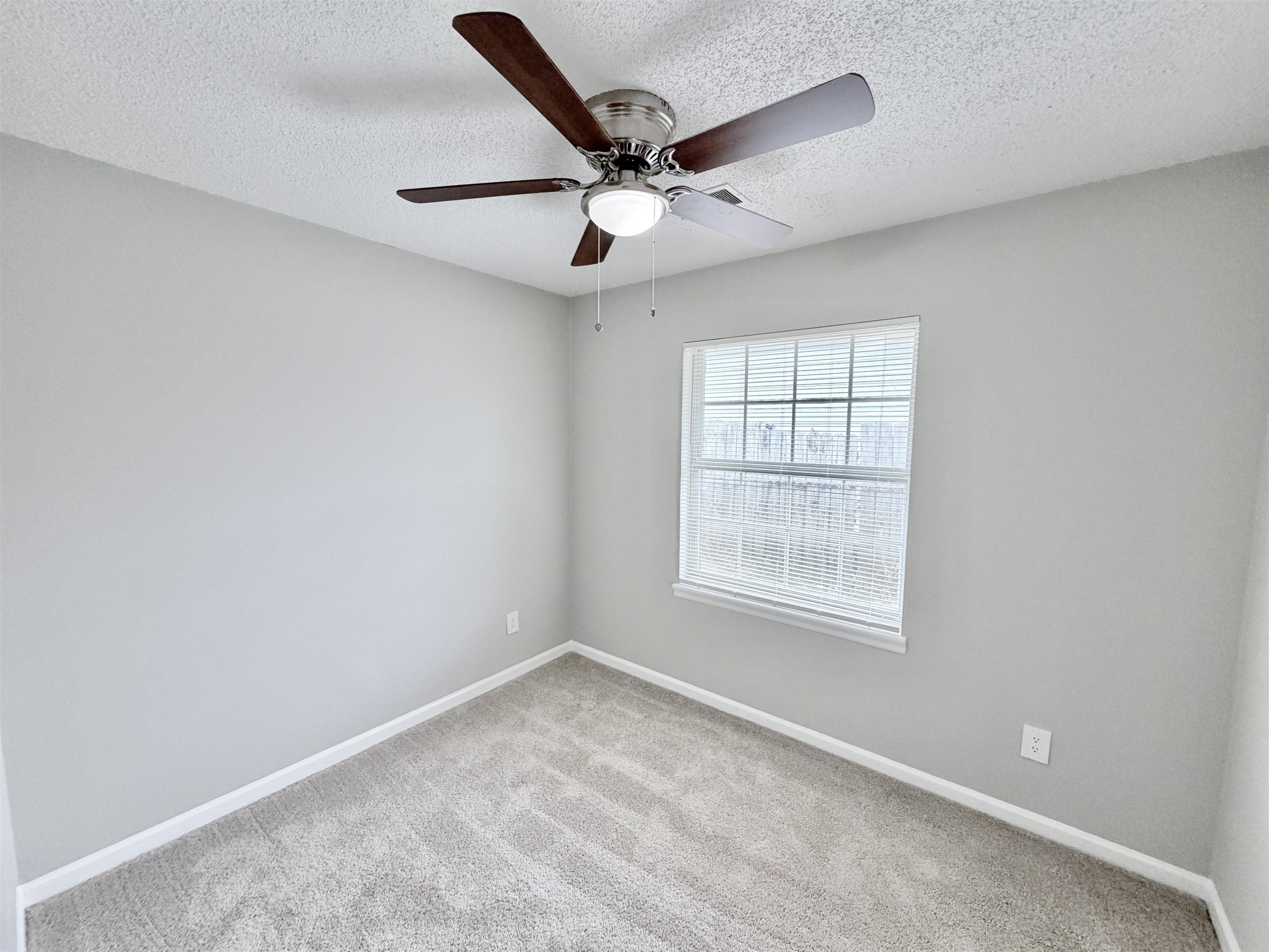 7830 Quito Road Millington, TN 38053 - Photo 22 of 26 an empty room with a ceiling fan and windows