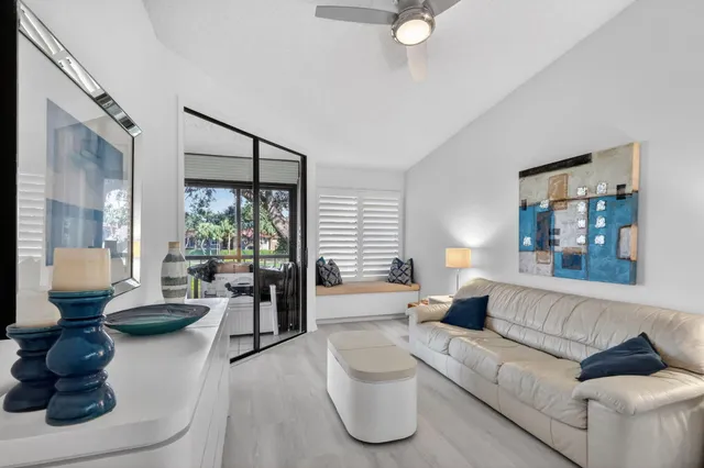 a large white kitchen with a large island stainless steel appliances a sink and a large window
