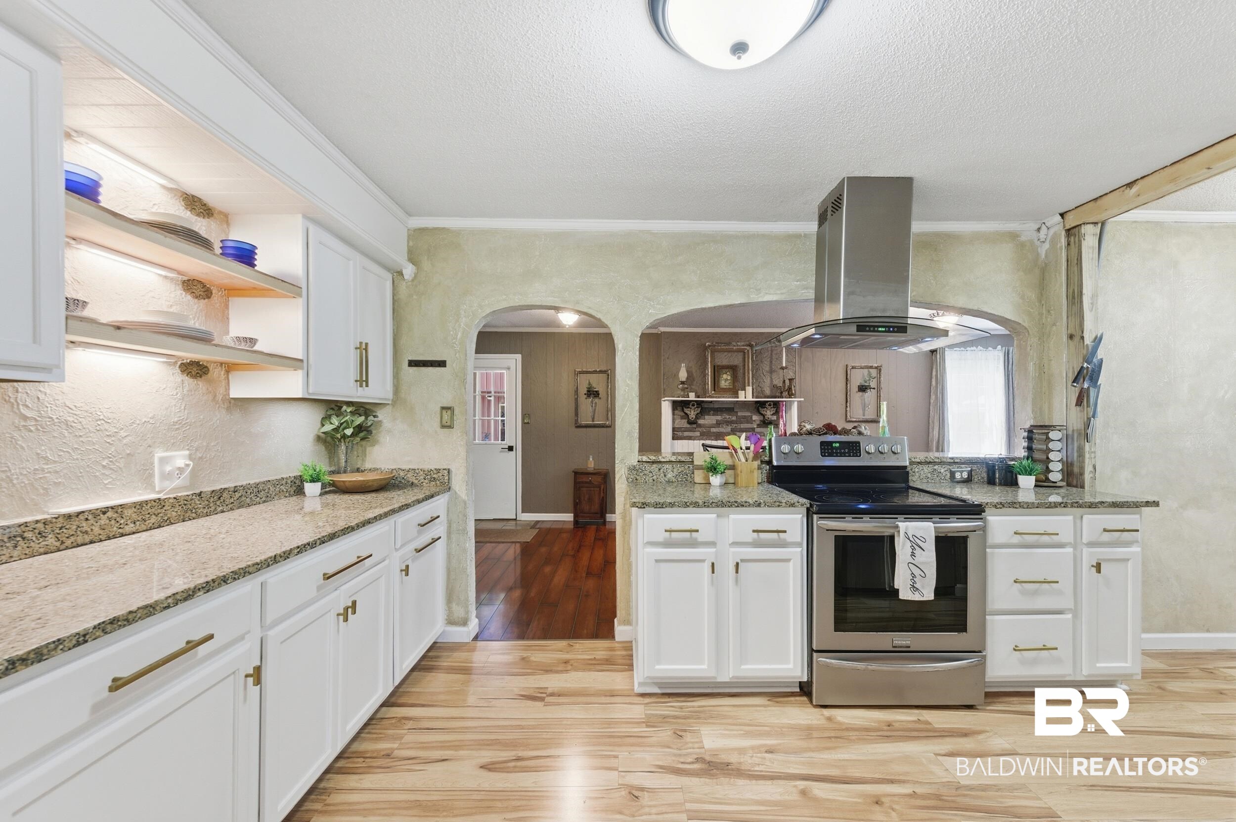 51620 Robert White Road Bay Minette, AL 36507 - Photo 32 of 81 Kitchen featuring wood-finish flooring, white cabinetry with brass hardware, light-colored countertops, a stainless steel range with overhead vent hood, and under-cabinet lighting