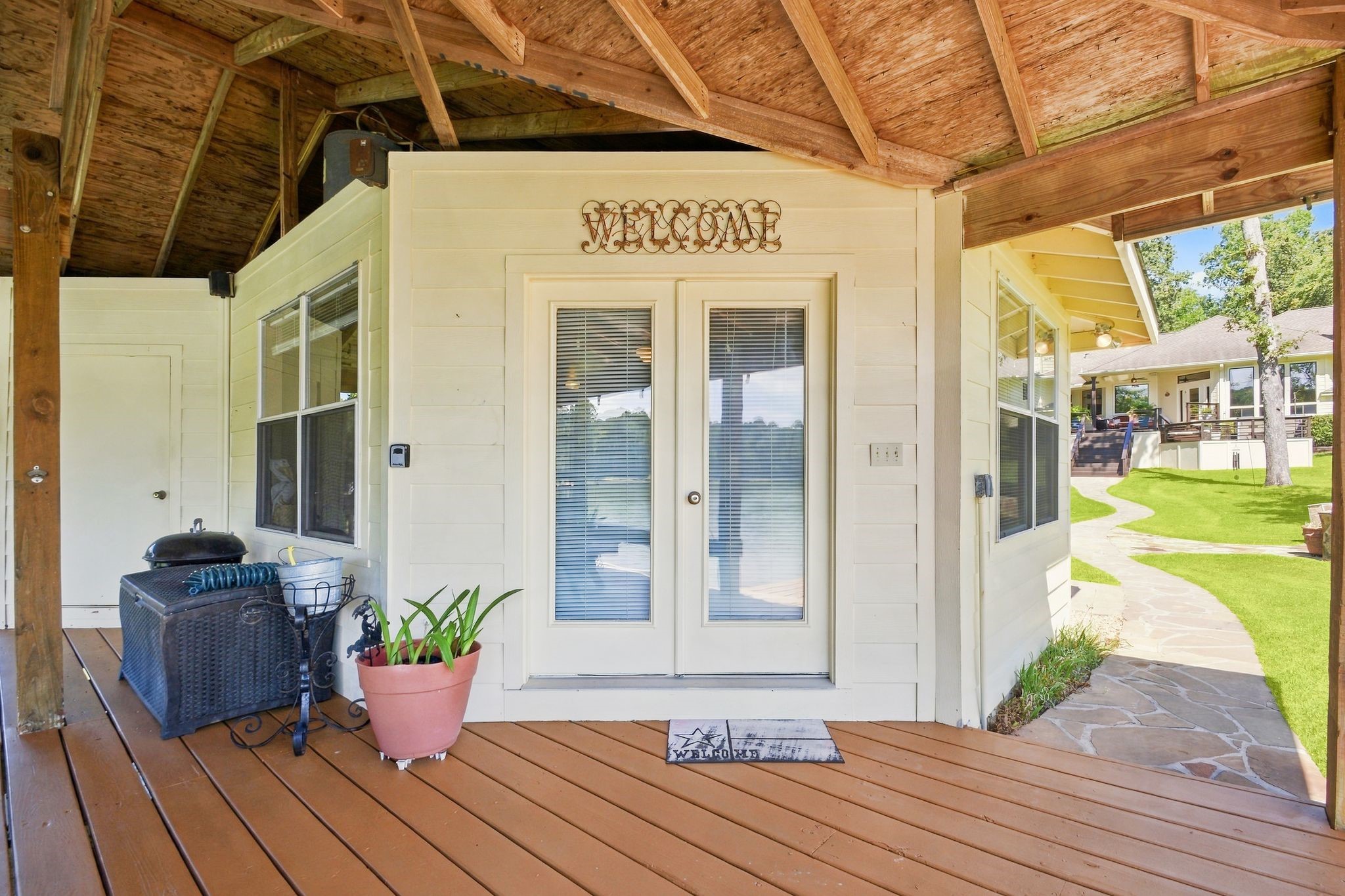 20341 Bay Hill Road Point Blank, TX 77364 - Photo 43 of 50 Private waterfront studio apartment entry with double glass doors, cozy seating, and inviting views of the backyard and surrounding greenery.