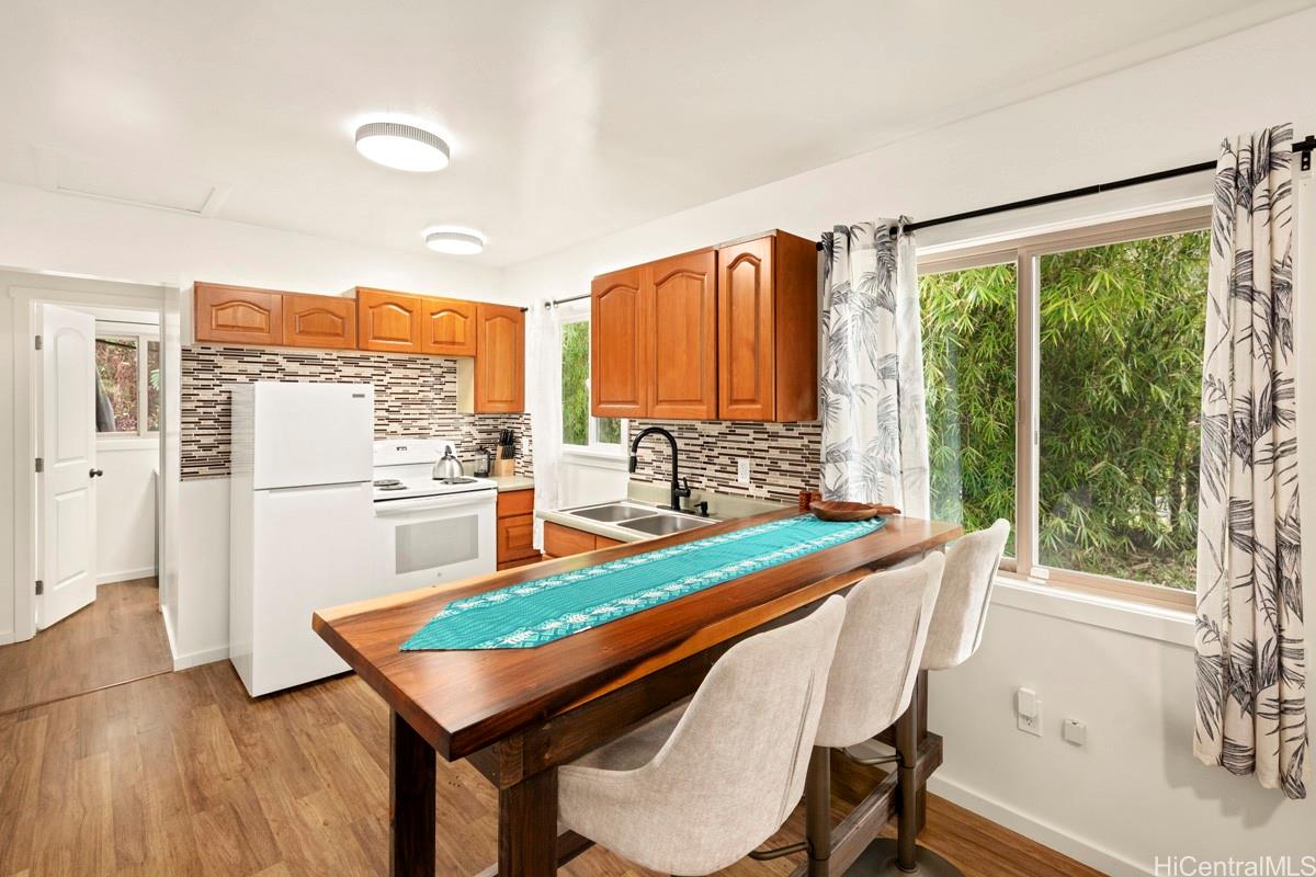 18-2274 Laulea Road Volcano, HI 96785 - Photo 3 of 15 Dining area with breakfast bar seating positioned alongside large windows overlooking the surrounding greenery