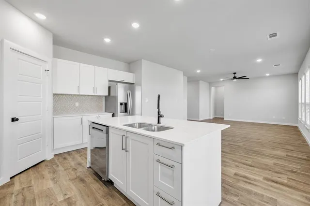 a kitchen with a sink stove and white cabinets with wooden floor