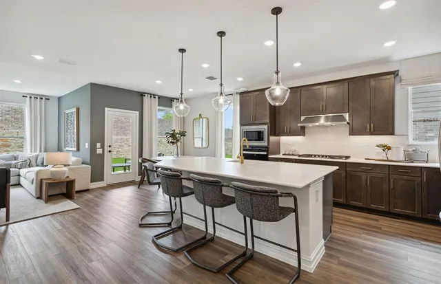 a kitchen with stainless steel appliances granite countertop a kitchen island hardwood floor sink stove dining table and chairs