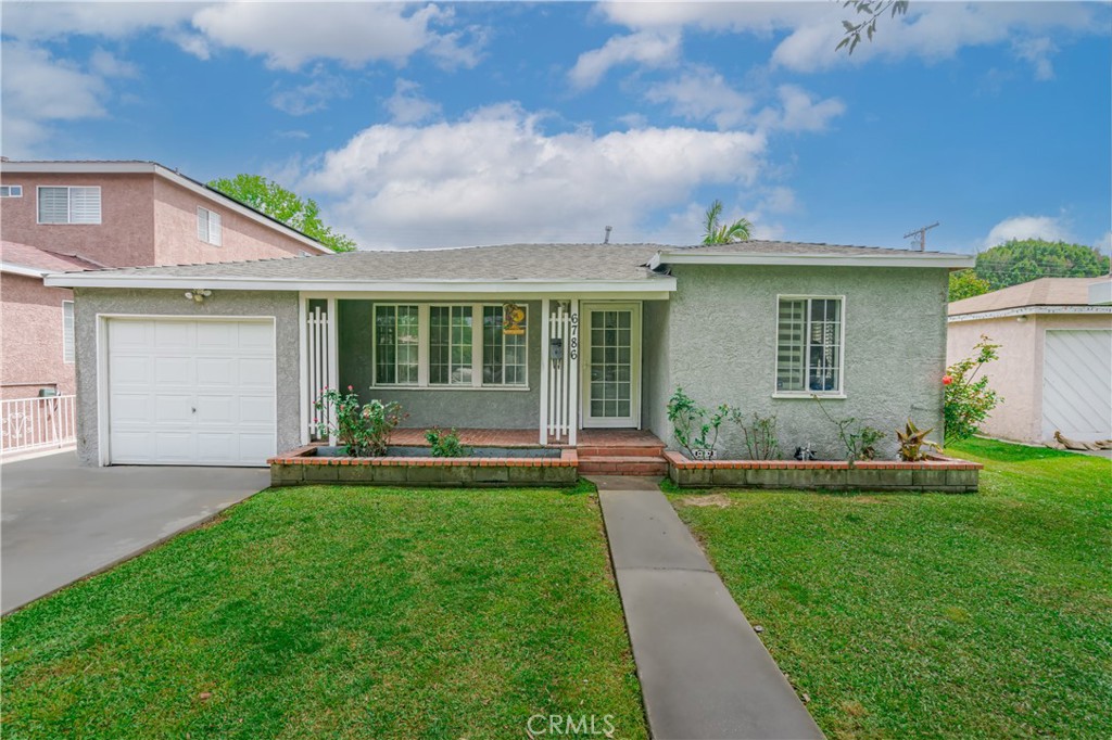 a front view of a house with a yard and potted plants