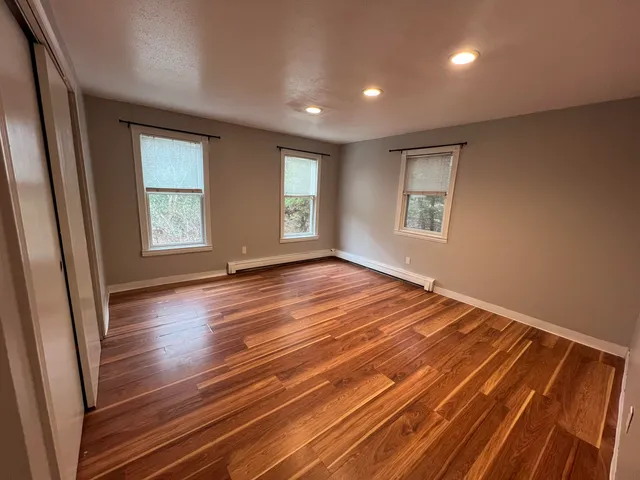 an empty room with wooden floor and windows