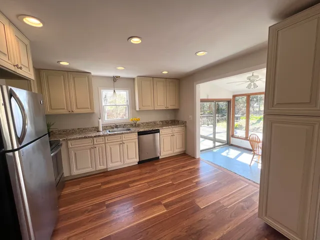 a kitchen with granite countertop a refrigerator and wooden floors