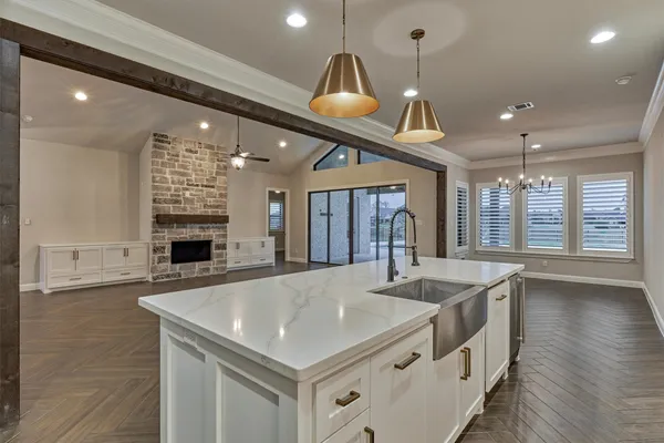a view of an empty room with wooden floor and a kitchen