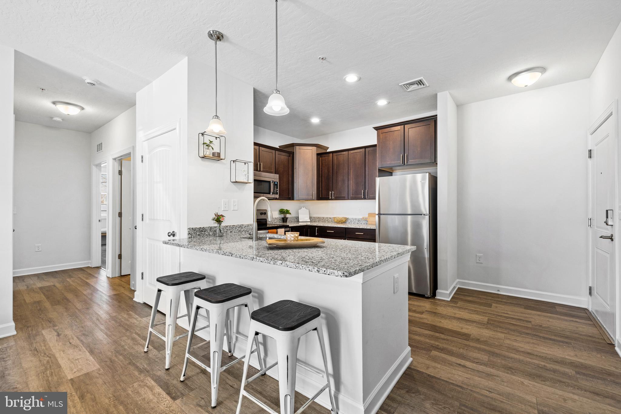 1201 Walnut Bottom Road, Unit 100103 Carlisle, PA 17015 - Photo 7 of 32 a kitchen with stainless steel appliances granite countertop a refrigerator a oven a sink a stove and white cabinets with wooden floor
