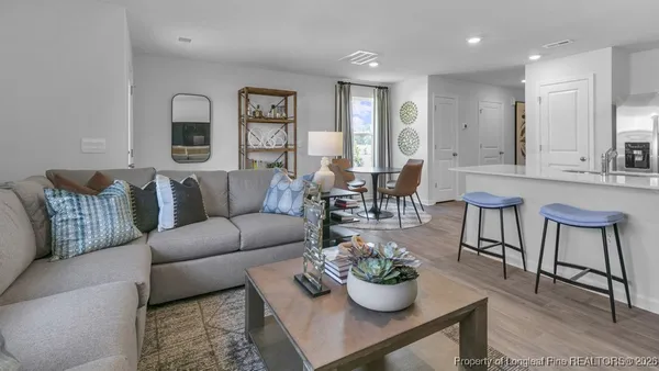 a living room with furniture potted plant and kitchen view