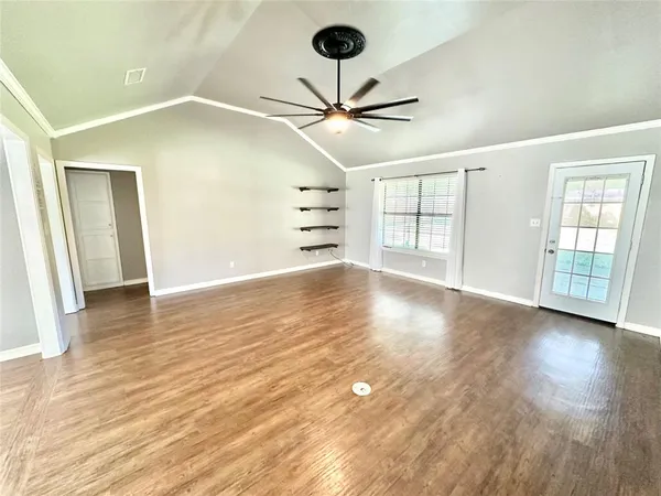 a view of an empty room with window and wooden floor
