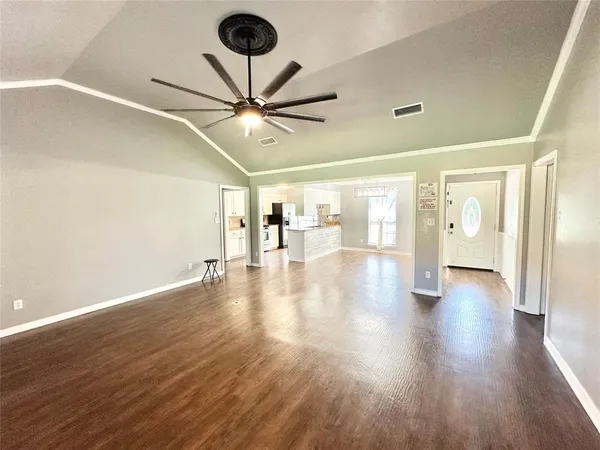 a view of an empty room with wooden floor and a ceiling fan