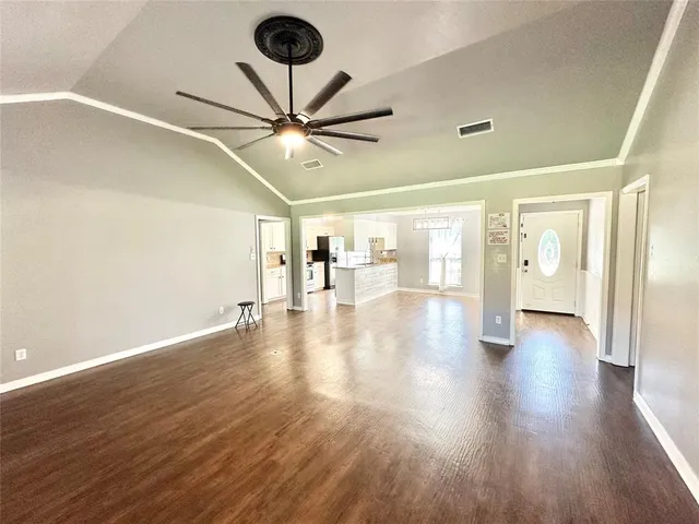a view of an empty room with wooden floor and a ceiling fan