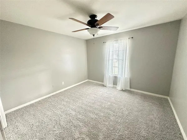 an empty room with a ceiling fan and window