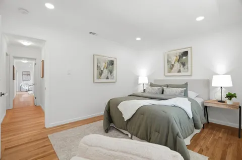 a spacious bedroom with two beds and painting on the wall