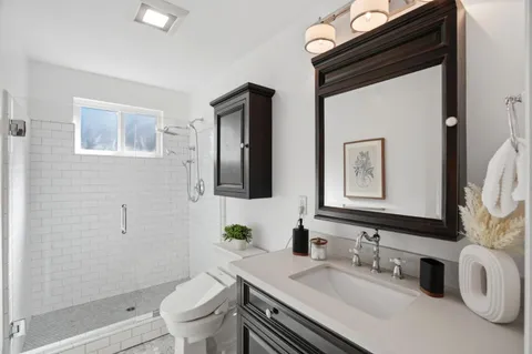 a bathroom with a granite countertop sink toilet and mirror
