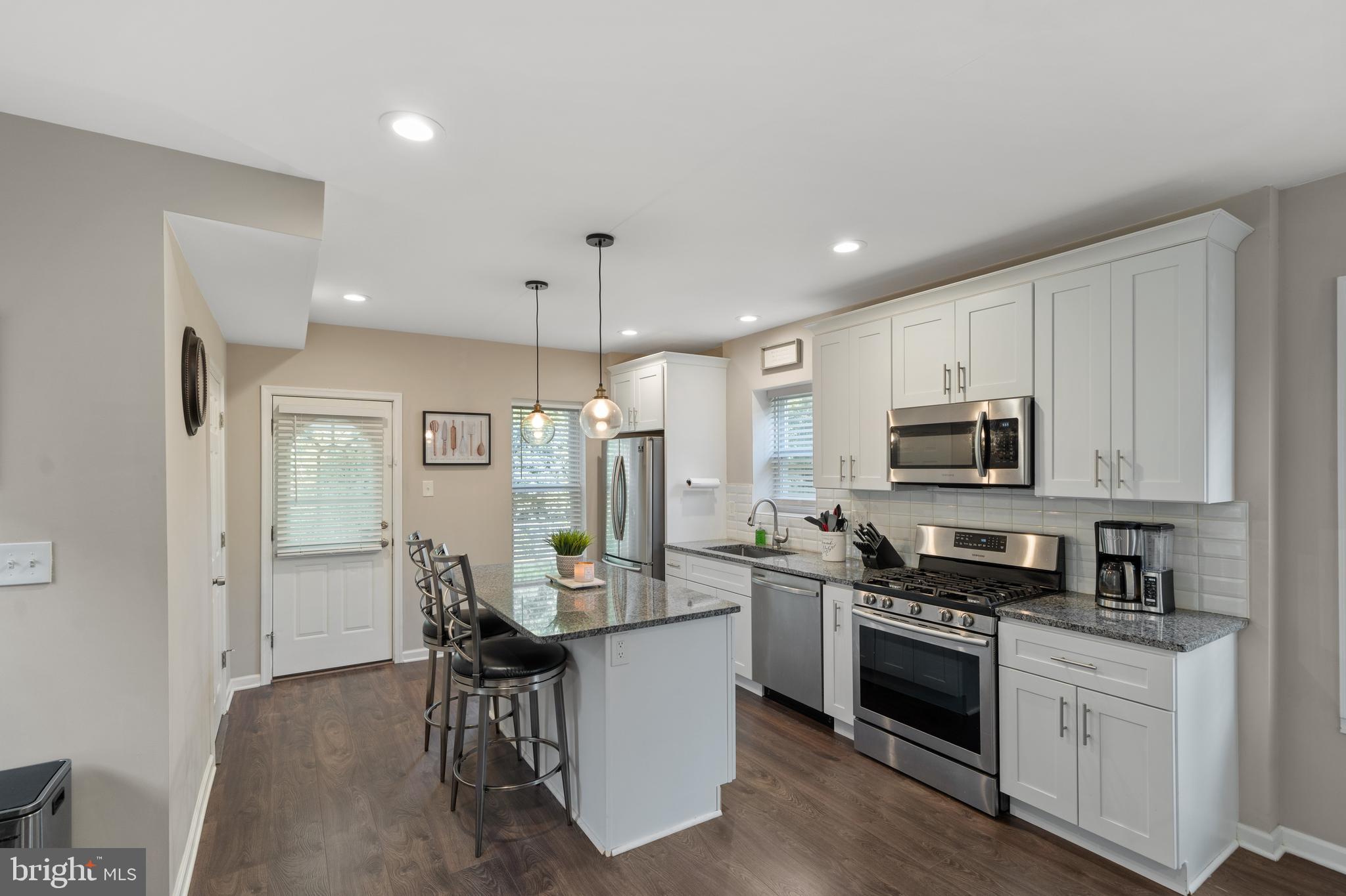 261 East Avon Road Brookhaven, PA 19015 - Photo 13 of 34 a kitchen with stainless steel appliances kitchen island granite countertop a refrigerator a stove a sink a dining table and chairs with wooden floor