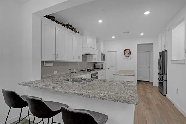 a kitchen with stainless steel appliances granite countertop a sink refrigerator and cabinets