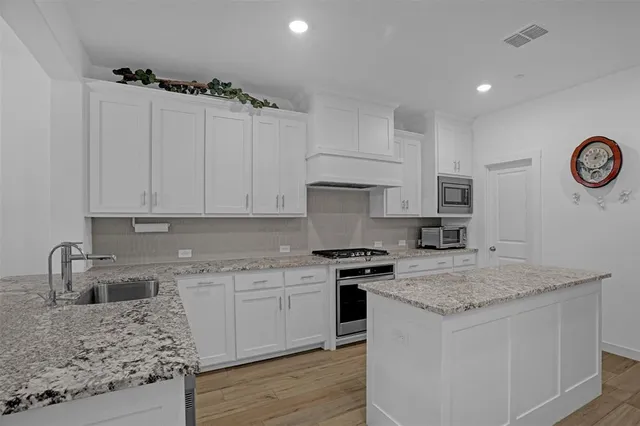 a kitchen with granite countertop a sink a stove and cabinets